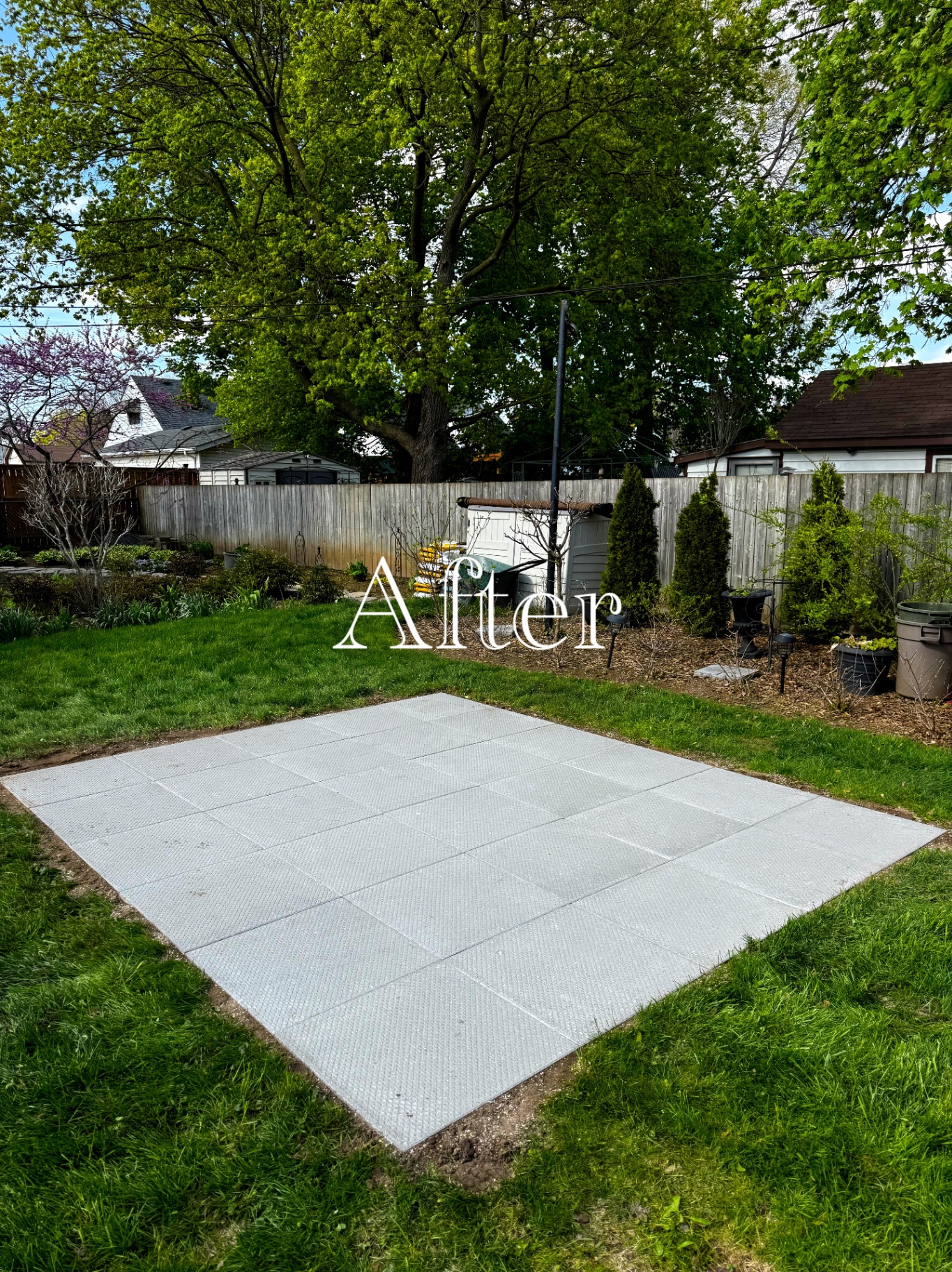 Finished grey slab patio set level in a backyard lawn.