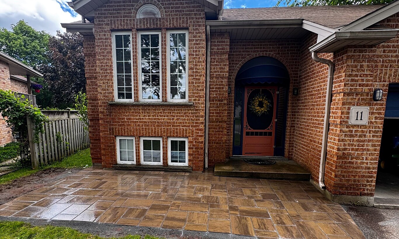 Newly installed interlocking paver front patio and walkway leading to the arched front entrance of a red brick home in Brantford.