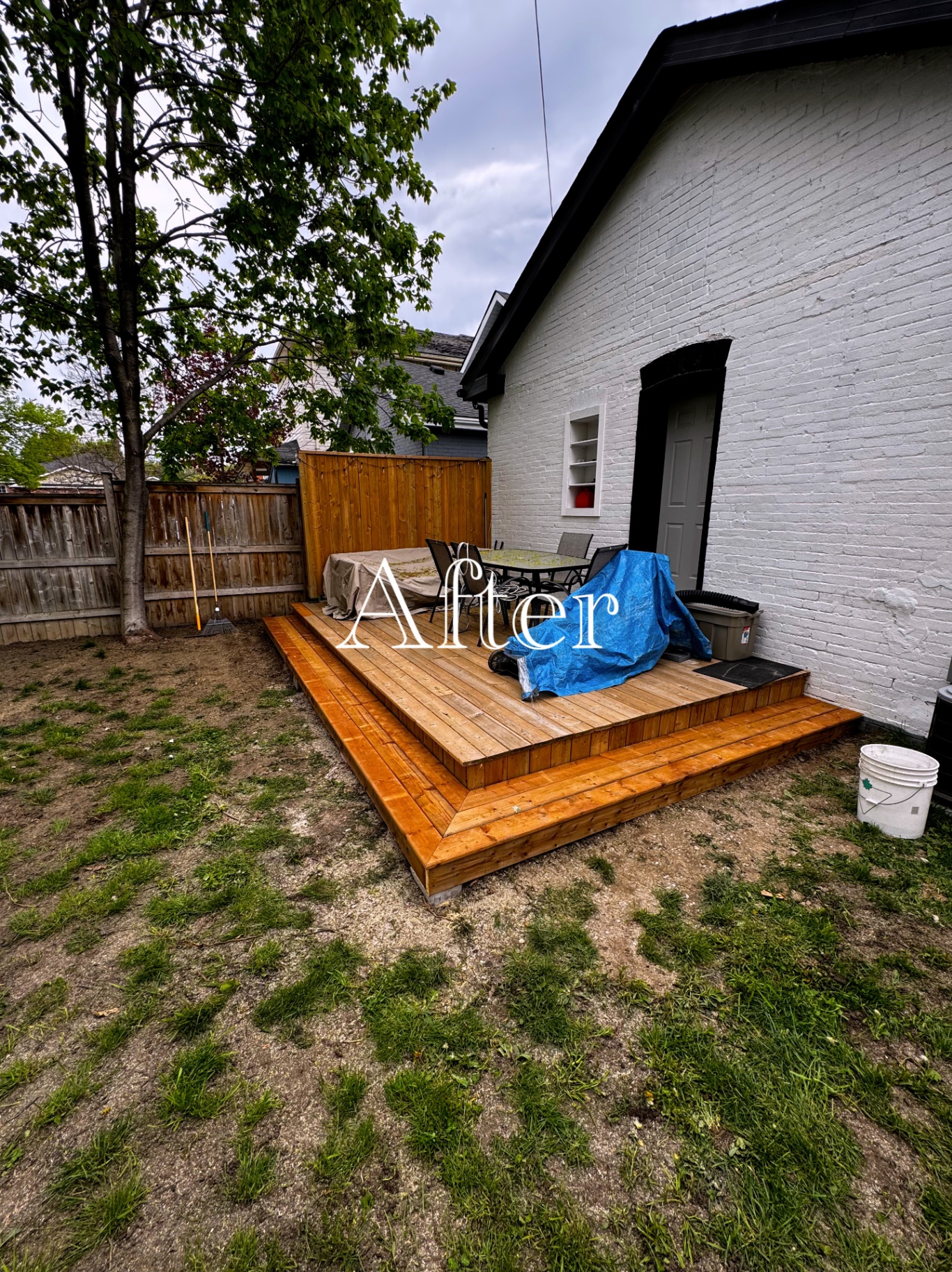 Finished cedar deck with wide steps built against a white brick house.