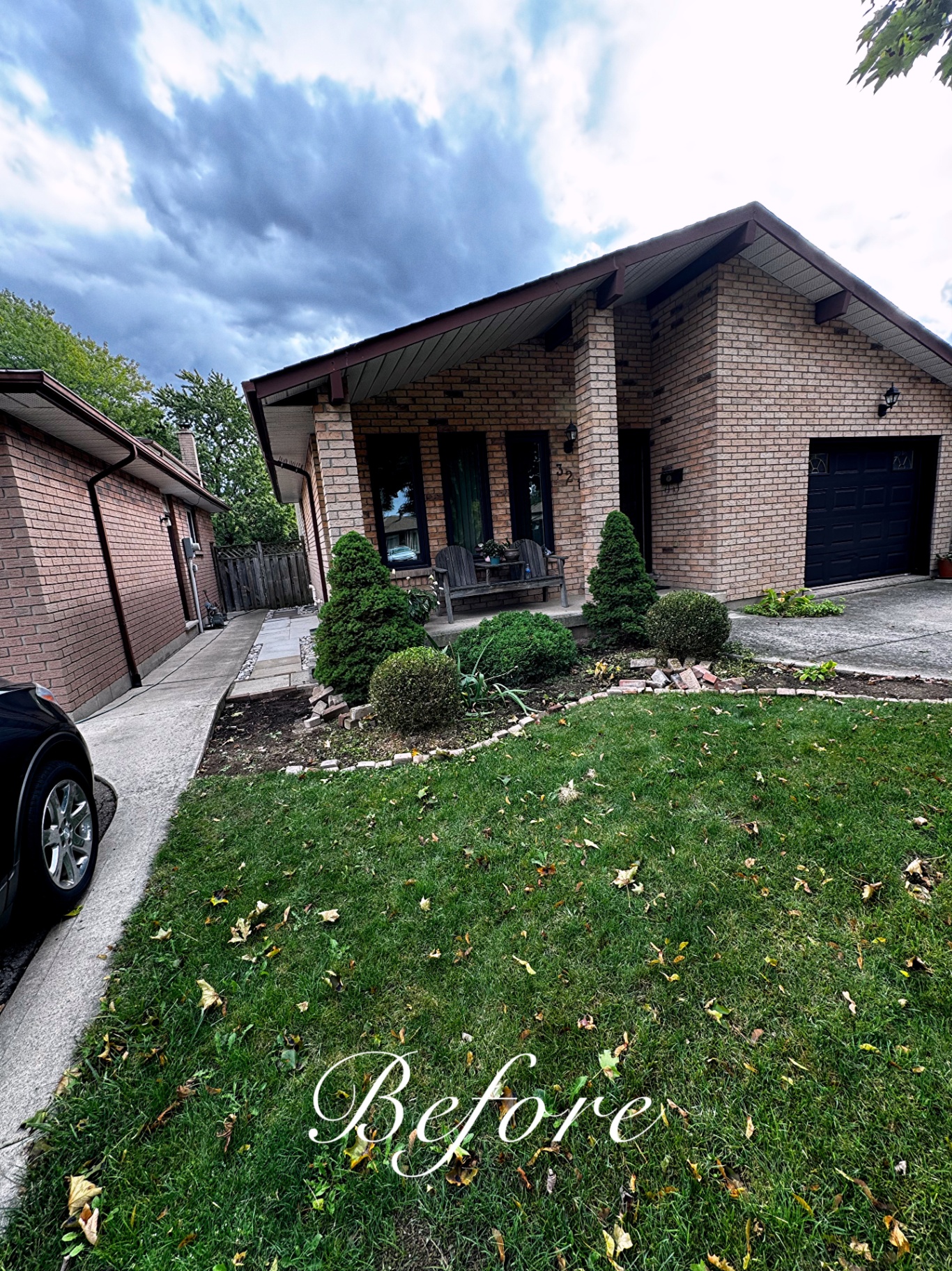 Front yard before cleanup with leaf-covered lawn, broken brick edging and tired beds.