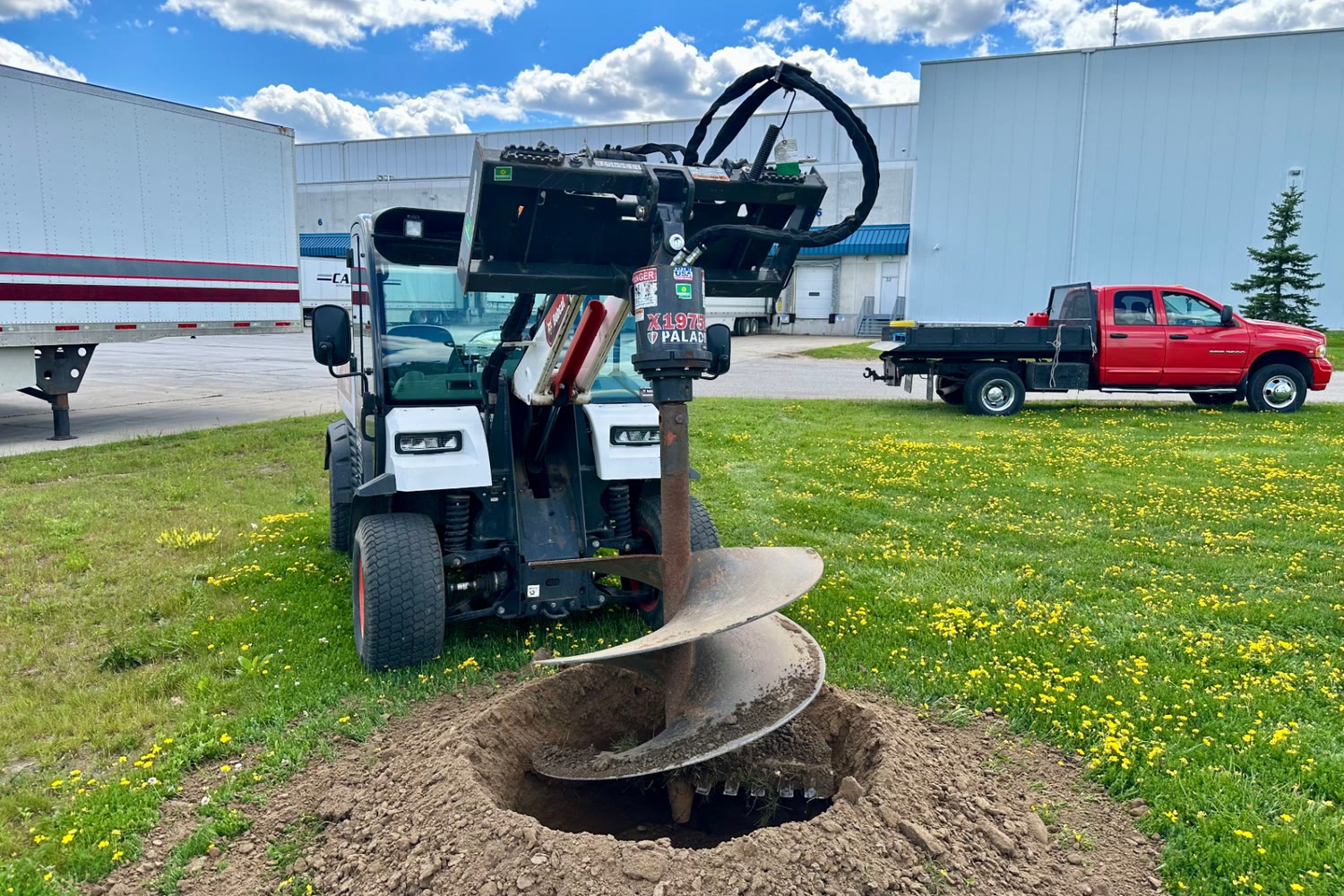 Close-up of a tree-planting auger mounted on a compact utility vehicle at a Brantford commercial site.